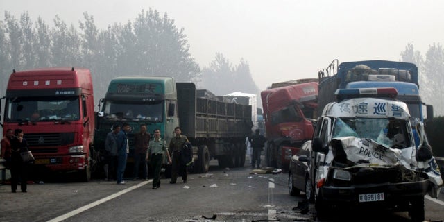 Oct. 7, 2011: People look at the damaged vehicles piled up on a highway road in Huaibei in central China's Anhui province. Three major road accidents in China killed at least 56 people on the last day of a weeklong holiday, including 35 people who died after a bus collided with a car on a northern expressway, state media reported Saturday.
