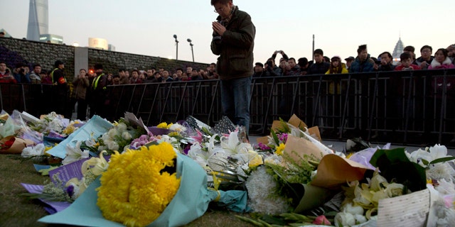 FILE - In this Thursday, Jan. 1, 2015 file photo, a man prays after laying flowers at the site of a New Years Eve deadly stampede in Shanghai. (AP Photo/Ng Han Guan, File)