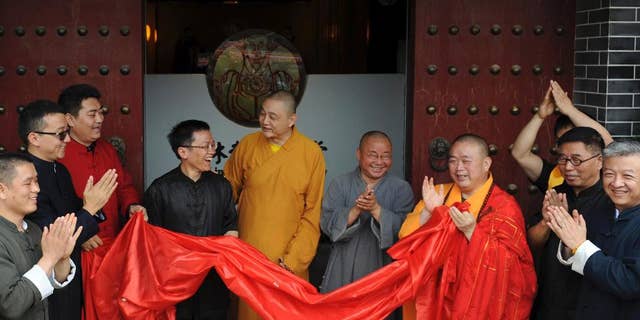 In this photo taken Sunday June 28, 2015, Shi Yongxin, third from right in yellow and red robes, abbot of the Shaolin Temple, attends the opening ceremony of an urban zen center named Shaolin Chan Hall in Xi'an in northwest China's Shaanxi province.  Chinese authorities are investigating allegations of misbehavior made online against the controversial abbot of China's famed Shaolin Temple. (Chinatopix Via AP) CHINA OUT