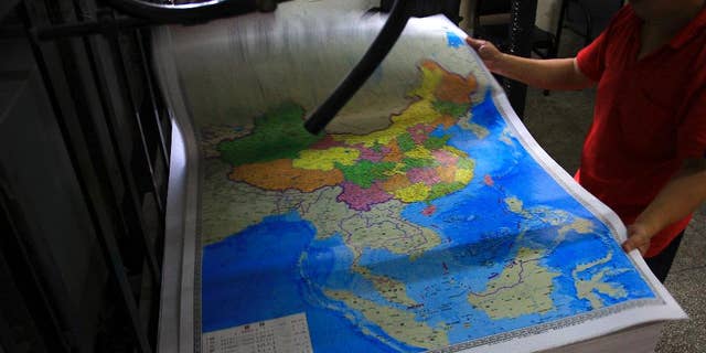 In this June 27, 2014 photo, a printing worker holds a new officially approved map of China that includes the islands and maritime area that Beijing claims in the South China Sea, at a factory in Changsha in south China's Hunan province. China has again rejected an attempt by the Philippines to challenge its territorial claims over the South China Sea through international arbitration, releasing a lengthy paper a week before the Dec. 15, 2014 deadline for China to respond to the case. China prefers to settle its disputes with discussions with the countries directly involved. But the Philippines has filed a case with an international tribunal.(AP Photo) CHINA OUT