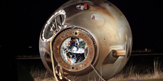 Nov. 17, 2011: A technician inspects the re-entry capsule of China's Shenzhou 8 spacecraft, which lies on its side with its hatch opened at a landing site in Siziwang Banner in north China's Inner Mongolia Autonomous Region. The unmanned Chinese spacecraft returned to Earth on Thursday night after it docked twice with an orbiting module in preparation for the country launching its own space station.