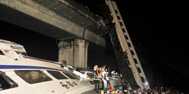 Emergency workers and people work to help passengers from the wreckage of train after two carriages from a high-speed train derailed and fell off a bridge in Wenzhou in east China's Zhejiang province Saturday July 23, 2011.