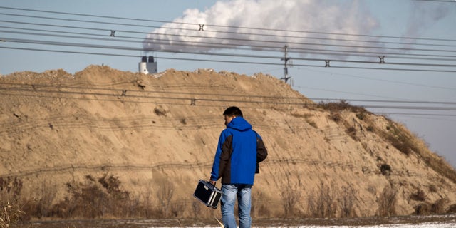 Dec. 3, 2011: Tan Liang, a resident carries a PM2.5 detector walks towards a garbage-burning facility, located near his residential compound in Beijing, China.