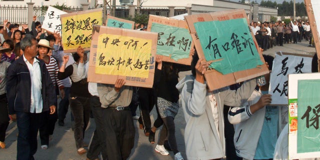 Dec. 15, 2011: Villagers hold placards chanting slogans as they march around their village during a protest in Wukan village, in China's Guangdong province. A man from a southern Chinese fishing village whose death in police custody helped spark a rare revolt was given a hero's farewell Friday as thousands of tearful residents mourned what they called his sacrifice for them.