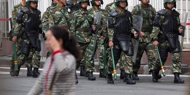FILE - In this May 23, 2014 file photo, paramilitary policemen with shields and batons patrol near the People's Square in Urumqi, China's northwestern region of Xinjiang.  So far this month, police in China's restive western region of Xinjiang have broken up 23 terror and religious extremism groups and caught over 200 suspects, state media reported Monday, May 26. (AP Photo/Andy Wong, File)