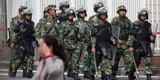FILE - In this May 23, 2014 file photo, paramilitary policemen with shields and batons patrol near the People's Square in Urumqi, China's northwestern region of Xinjiang. So far this month, police in China's restive western region of Xinjiang have broken up 23 terror and religious extremism groups and caught over 200 suspects, state media reported Monday, May 26. (AP Photo/Andy Wong, File)
