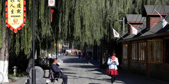 Nov. 9, 2014 - FILE photo of woman walking past a shop in Huairou district where the g Asia-Pacific Economic Cooperation (APEC) summit met in Beijing, China. For the first time in decades, the U.S. is no longer the largest economy in the world, and China has become number one.