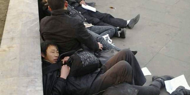 In this photo taken Dec. 10, 2013, which The Associated Press obtained on Wednesday, Dec. 11, 2013, from a friend of the petitioners, Chinese residents from Wuhan province lie on the ground after drinking pesticide near a historic watchtower in the heart of Beijing, China. A dozen central Chinese city residents protesting the demolition of their homes drank pesticide in Beijing in a desperate bid for attention that underscores the failures of a decades-old petitioning system. The photo has been authenticated based on its contents and other AP reporting.