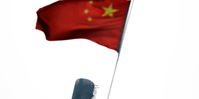 A Chinese national flag is seen in front of the chimney of a heat supply plant in Beijing July 16, 2014.