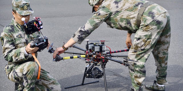April 21, 2015: A pair of militia members prepare to fly drones during a test in Shanghai, China.