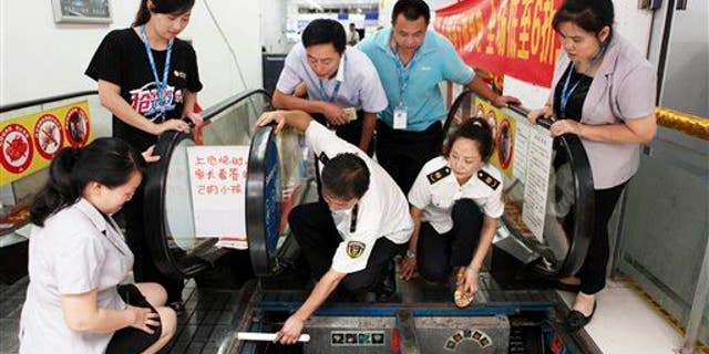 Staff members at an appliance store watch as officials from the local bureau of Quality and Technical Supervision inspect an escalator in Yongchuan district in Chongqing Municipality, July 30, 2015.