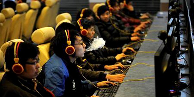 A man smokes while using a computer at an Internet cafe in Taiyuan, Shanxi province December 30, 2010. China shut down more than 60,000 pornographic websites this year, netting almost 5,000 suspects in the process, a government spokesman said on Thursday, vowing no let-up in its campaign against material deemed obscene.
