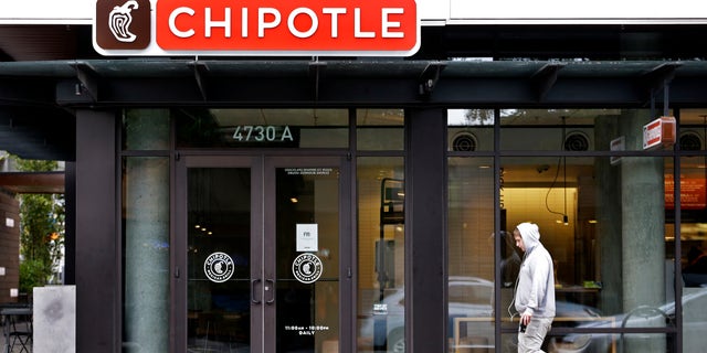 A pedestrian walks past a closed Chipotle restaurant Monday, Nov. 2, 2015, in Seattle. An E. coli outbreak linked to Chipotle restaurants in Washington state and Oregon has sickened nearly two dozen people in the third outbreak of foodborne illness at the popular chain this year. Cases of the bacterial illness were traced to six of the fast-casual Mexican food restaurants, but the company voluntarily closed down 43 of its locations in the two states as a precaution. (AP Photo/Elaine Thompson)