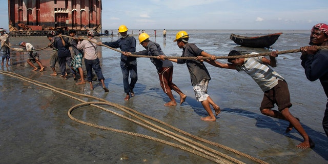 Workers haul a ship to shore for salvage at a ship-breaking yard in Chittagong, Bangladesh.