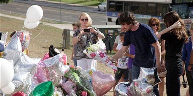 July 24, 2012: Actor Christian Bale, second right, and his wife Sibi Blazic, right, place flowers on a memorial to the victims of Friday's mass shooting in Aurora, Colo.