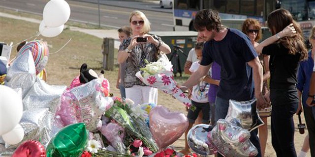 July 24, 2012: Actor Christian Bale, second right, and his wife Sibi Blazic, right, place flowers on a memorial to the victims of Friday's mass shooting in Aurora, Colo.