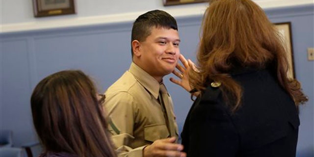 Lance Cpl. Christopher Mohedano-Hernandez, center, is hugged by family members after participating in an adoption ceremony in Mineola, N.Y., Tuesday, Dec. 24, 2013. The U.S. Marine home on leave has been formally adopted by his stepfather in a Christmas Eve adoption ceremony held in a suburban New York courtroom. Mohedano-Hernandez is the latest in what experts call a growing trend of adult adoptions. (AP Photo/Seth Wenig)