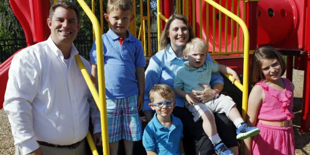 In this May 29, 2014 photo, Christy Wolford holds her youngest son Lucas, 2, as her husband Bubba and other children Lauren, 8, Alexander, 4, and Everett, 3, are pictured at the Primrose School the couple runs in Fort Collins, Colo. Christy Wolford's ovaries were suppressed during cancer treatment and she has had three boys since it ended in 2006. (AP Photo/Ed Andrieski)