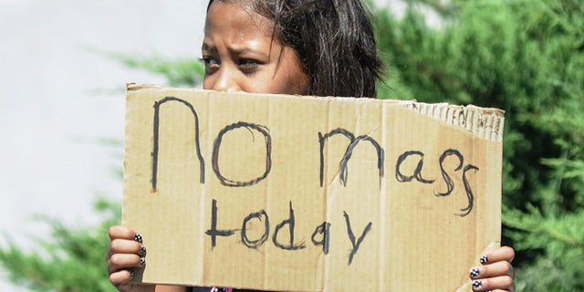 Aaliyah Doninguez, 11, stands on N. Alameda Boulevard on Sunday, Aug. 2, 2015, in Las Cruces, N.M., advising parishioners that Holy Cross Catholic Church mass is canceled. Churchgoers were left shaken during Sunday morning services after authorities say explosions occurred less than 30 minutes apart outside two Las Cruces churches. (Robin Zielinski/The Las Cruces Sun-News via AP) MANDATORY CREDIT