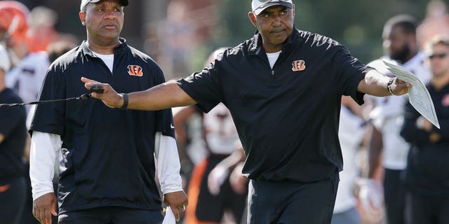 Cincinnati Bengals coach Marvin Lewis, right, signals to his players alongside offensive coordinator Hue Jackson, left, during a joint NFL football training camp with the New York Giants, Wednesday, Aug. 12, 2015, in Cincinnati. (AP Photo/John Minchillo)