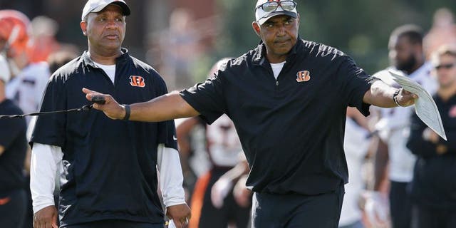 Cincinnati Bengals coach Marvin Lewis, right, signals to his players alongside offensive coordinator Hue Jackson, left, during a joint NFL football training camp with the New York Giants, Wednesday, Aug. 12, 2015, in Cincinnati. (AP Photo/John Minchillo)
