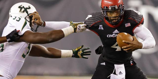 FILE - In this Oct. 24, 2014, file photo, Cincinnati quarterback Munchie Legaux (4) is sacked by South Florida linebacker Josh Black (55) during the second half of an NCAA college football game in Cincinnati. Gunner Kiel reaggravated his ribs, leaving it up to Legaux to pull Cincinnati through. It worked against South Florida (AP Photo/Al Behrman, File)