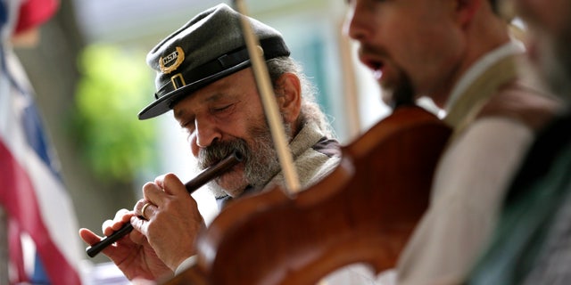 In this June 16, 2012 photo, Greg Hernandez plays a fife during a performance with the 2nd South Carolina String Band in Hagerstown, Md. Some re-enactors have formed camp bands to play music that soldiers enjoyed hearing around battlefield campfires. The most popular tunes included songs from the minstrel stage. Groups such as the 2nd South Carolina String Band pride themselves on their accurate impressions right down to the exaggerated black dialect of songs with inescapably racist overtones. (AP Photo/Patrick Semansky)