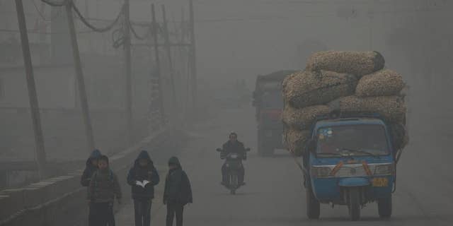 FILE - In this Feb. 26, 2014 file photo, children walk back home after school on a severely polluted day in Shijiazhuang, in northern China's Hebei province. A groundbreaking agreement struck Wednesday, Nov. 12, 2014, by the United States and China puts the world's two worst polluters on a faster track to curbing the heat-trapping gases blamed for global warming. (AP Photo/Alexander F. Yuan, File)