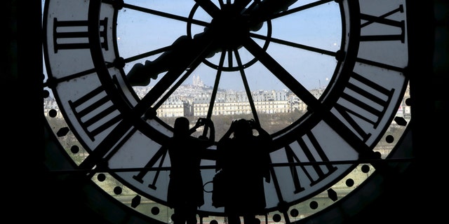File photo - Visitors at the Musee d'Orsay are seen in silhouette as they take pictures from behind a giant clock face April 8, 2015.