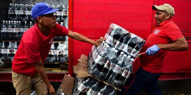 Workers unload bottles of Coca Cola from a truck in Caracas on May 27, 2016. Coca Cola suspended much of its distribution in Venezuela due to a shortage of sugar. / AFP / RONALDO SCHEMIDT (Photo credit should read RONALDO SCHEMIDT/AFP/Getty Images)