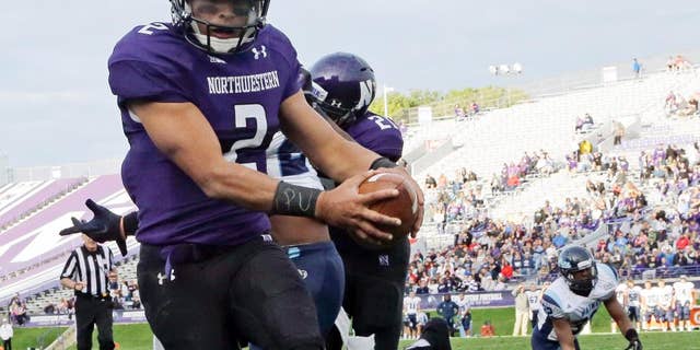 FILE - In this Sept. 21, 2013, file photo, Northwestern quarterback Kain Colter (2), wears APU for "All Players United" on wrist tape as he scores a touchdown during an NCAA college football game against Maine in Evanston, Ill. The five-member regulatory board that will ultimately decide if Northwestern University football players can unionize has itself been in the middle of a firestorm. The very makeup of the National Labor Relations Board has been challenged in a case now before the Supreme Court. And Republicans contend the agency has being overly friendly to organized labor. (AP Photo/Nam Y. Huh, File)
