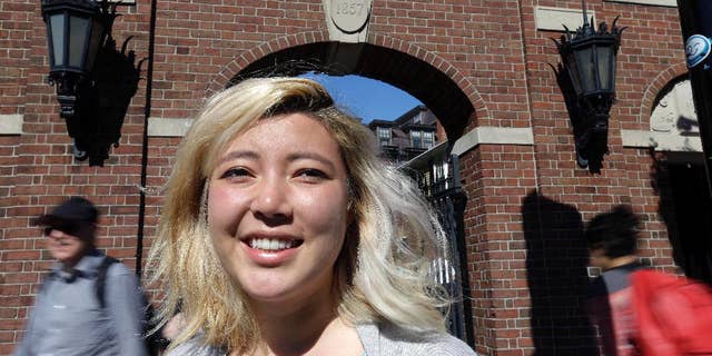 In this Thursday, Sept. 17, 2015 photo, Laila Smith, a junior at Harvard University, poses at a gate leading to Harvard Yard in Cambridge, Mass. During the registration process, students at Harvard are now allowed to indicate which pronouns they use. Forms include typical options like “he” and “she” but also gender-neutral options like “ze” or “they.” Smith filled in the pronouns “they” and “their” on the form. (AP Photo/Steven Senne)
