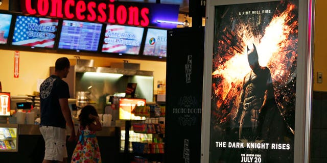 FILE - In this July 20, 2012 file photo, people walk past a "The Dark Knight Rises," at Regal Cinemas at Crossgates Mall in Albany, N.Y.