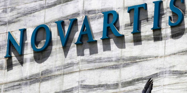 FILE - In this April 1, 2013 file photo, a dove flies near the logo of Novartis India Limited at their head office in Mumbai, India. Colombiaâs government announced on Tuesday, May 17, 2106, that it is giving pharmaceutical giant Novartis a few weeks to lower prices on a popular cancer drug or see its monopoly on production of the medicine broken and competition thrown open to generic rivals. (AP Photo/Rafiq Maqbool, File)