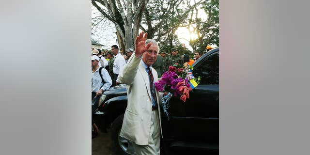 Britain's Prince Charles, right, waves towards local residents as he holds a bouquet of flowers that was given to him during a visit to La Macarena, Colombia, Thursday, Oct. 30, 2014. Prince Charles and his wife Camilla are in Colombia as part of a nine-day tour of Latin America. (AP Photo/Fernando Vergara)