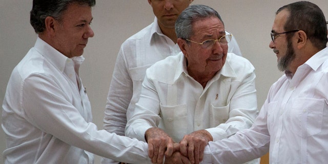 Cuba's President Raul Castro, center, encourages Colombian President Juan Manuel Santos, left, and Commander the Revolutionary Armed Forces of Colombia or FARC, Timoleon Jimenez to shake hands, in Havana, Cuba, Wednesday, Sept. 23, 2015. In a joint statement, Santos and the FARC said they have overcome the last significant obstacle to a peace deal by settling on a formula to compensate victims and punish belligerents for human rights abuses. (AP Photo/Desmond Boylan)