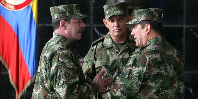 FILE - In this Feb. 18, 2014, file photo, the new Colombian armed forces commander Gen. Juan Pablo Rodríguez, right, talks to newly appointed chief of staff Gen. Javier Florez, left, and army commander Gen. Jaime Lasprilla, center, after a press conference where Defense Minister Juan Carlos Pinzon announced the firing of the fromer armed forces chief Gen. Leonardo Barrero in Bogotá, Colombia. Gen. Rodríguez and Gen. Lasprilla are among dozens of senior Colombian army officers implicated in the killing of 3,000 civilians falsely claimed to be rebels a decade ago have risen through the ranks and are escaping punishment for their roles in one of the worst atrocities committed in Latin America, Human Rights Watch said Wednesday, June 23, 2015. (AP Photo/Fernando Vergara, File)