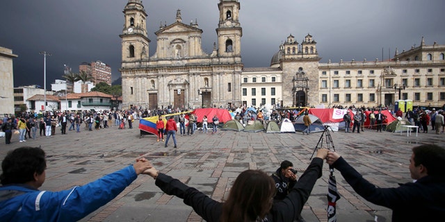 Demonstrators hold hands to support a peace accord between the Colombian government and rebels of the Revolutionary Armed Forces of Colombia, FARC, at the main square in Bogotá, Colombia, Saturday, Oct. 8, 2016. Dozens of people are camping at the Bolívar square in support of the peace process. Voters narrowly rejected in a referendum a peace accord signed between President Juan Manuel Santos and the FARC. (AP Photo/Ivan Valencia)