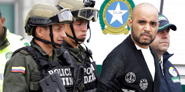 Alleged Peruvian drug trafficker Gerson Galvez, right, is escorted by police officers to a waiting Peruvian Air Force plane, in Bogota, Colombia, Sunday, May 1, 2016. Galvez who is one of Peru's most wanted criminals was captured by the Colombian police in Medellín on Saturday and was handed over to the Peruvian authorities. (AP Photo/Fernando Vergara)
