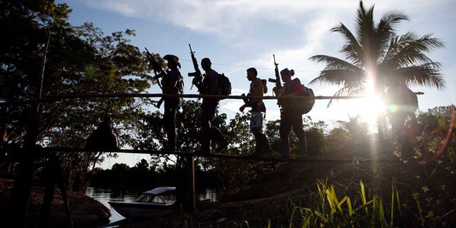 In this Aug. 12, 2016 photo, rebels of the 48th Front of the Revolutionary Armed Forces of Colombia walk on a makeshift footbridge in the southern jungles of Putumayo, Colombia. With the peace accords about to signed between the FARC and the governemt, gone are the days when they had to change camp every few days for fear of being stunned in their sleep by bombs falling from the skies. (AP Photo/Fernando Vergara)