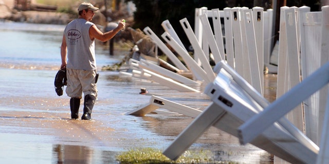 A man wades through the flood waters Sept. 18, 2013 in Evans, Colo. Residents are advised to wash everything that comes in contact with the water. (AP Photo/The Greeley Tribune, Joshua Polson)