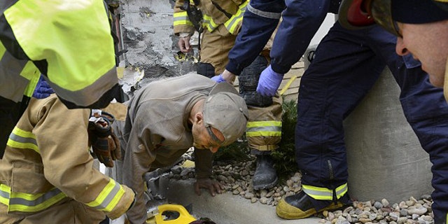 November 11, 2014: A man trapped in a wall at the rear of a Marshalls store in Longmont, Colo., crawls out of a hole and onto a backboard. Longmont Police Sgt. Matt Cage said Paul Felyk, 35, was taken to Longmont United Hospital after falling about 20 feet inside the walls and becoming trapped. (AP Photo/The Daily Times Call, Lewis Geyer)