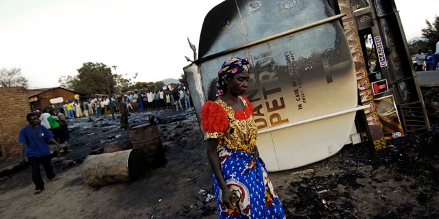 July 3: An inhabitant of the town of Sange, eastern Congo, walks past the burned out wreckage of a tanker truck involved in a accident Friday night.