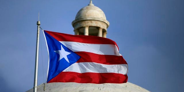 FILE - In this July 29, file 2015 photo, the Puerto Rican flag flies in front of Puerto Rico's Capitol as in San Juan, Puerto Rico. Congress edged closer to delivering relief to debt-stricken Puerto Rico as the Senate on Wednesday, June 29, 2016, cleared the way for passage of a last-minute financial rescue package for the territory of 3.5 million Americans. (AP Photo/Ricardo Arduengo, File)