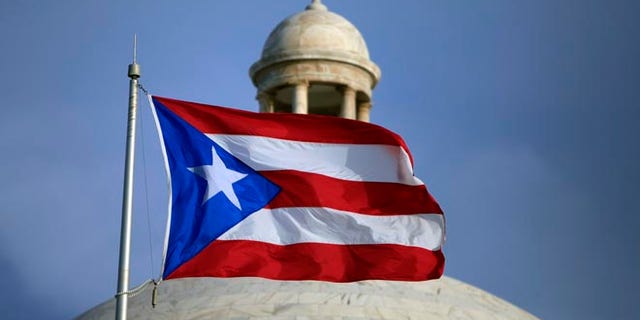 FILE - In this July 29, file 2015 photo, the Puerto Rican flag flies in front of Puerto Rico's Capitol as in San Juan, Puerto Rico. Congress edged closer to delivering relief to debt-stricken Puerto Rico as the Senate on Wednesday, June 29, 2016, cleared the way for passage of a last-minute financial rescue package for the territory of 3.5 million Americans. (AP Photo/Ricardo Arduengo, File)