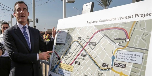 Los Angeles Mayor Eric Garcetti looks at the proposed "Regional Connector Transit Project" plan as he attends a federal grant signing ceremony in Los Angeles Thursday, Feb. 20, 2014. The light rail public transit system in Los Angeles is getting $670 million to solve one of its most vexing design deficiencies: Train riders who want to travel from one side of downtown and out the other must transfer twice. The "regional connector," as the Los Angeles County Metropolitan Transportation Authority calls it, will tie together three existing light rail lines with a new tunnel and three new stations. Major construction should begin later this year, with a cost estimated of $1.4 billion, to be opened in 2020. (AP Photo/Damian Dovarganes)