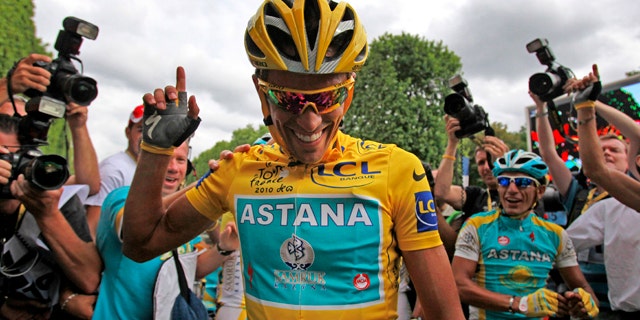 July 25, 2010: Three-time Tour de France winner Alberto Contador of Spain is flanked by teammates and photographers after the 20th and last stage of the tour.