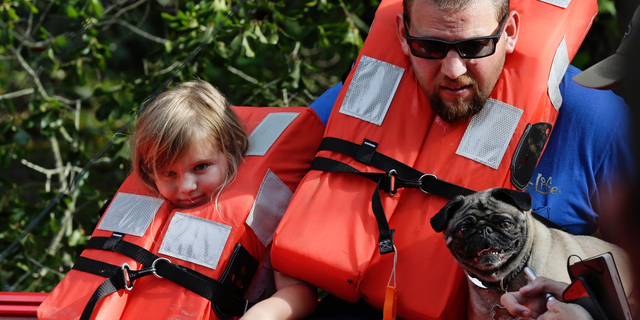 Brent Lamb, right, and his daughter Laci, 4, are removed from a flooded neighborhood by members of the U.S. Coast Guard Shallow Water Rescue Team in Lumberton, N.C., Monday, Sept. 17, 2018, following flooding from Hurricane Florence. (AP Photo/Gerry Broome)