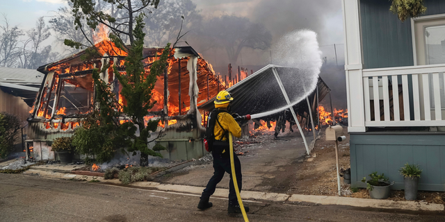 Firefighters battle flames at the Alpine Oaks Estates mobile home park during a wildfire Friday in Alpine, California.