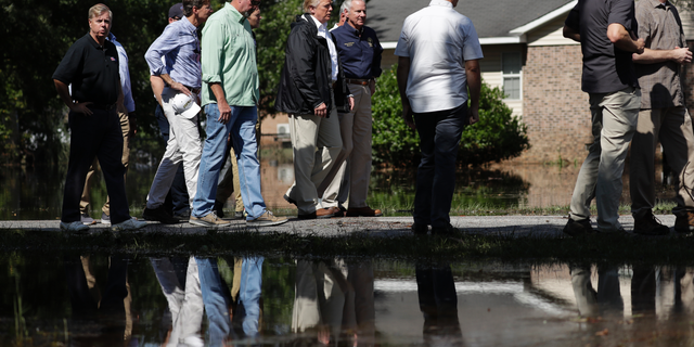 President Donald Trump visits a neighborhood impacted by Hurricane Florence, Wednesday, Sept. 19, 2018, in Conway, S.C. Next to Trump is South Carolina Gov. Henry McMaster. (AP Photo/Evan Vucci)